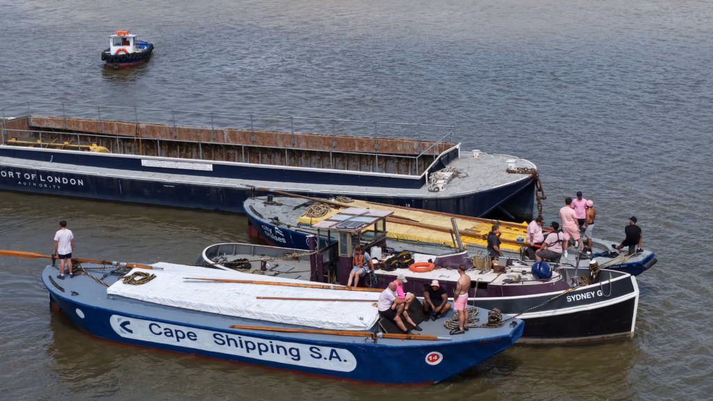 Barges lettered for the Port of London Authority and Cape Shipping S.A. rafted together with their crews before the race