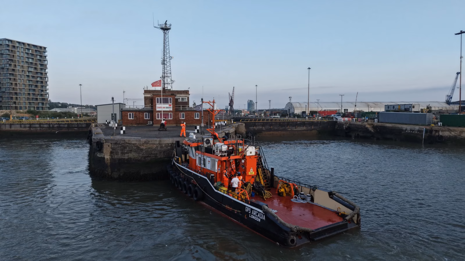 Aerial photograph of the tug GPS Arcadia approaching the dockyard wall at Chatham in early morning light for a crew transfer
