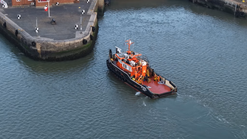 The tug GPS Arcadia making her approach to the quay wall at Chatham Docks on the River Medway, seen from above