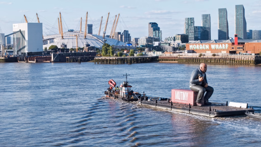 Mutiny: Jason Statham Brand Activation on the Thames 6 The Mutiny brand activation being towed past Morden Wharf on the Greenwich Peninsula, with the O2 and Canary Wharf beyond