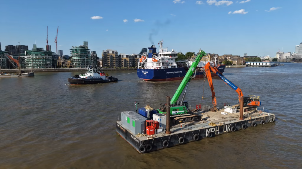The AGD Equipment crane aboard the TMS Seavoyager pontoon at sunset on the Thames, City of London behind