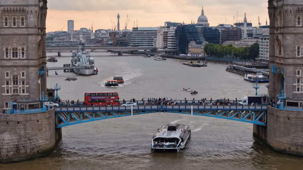 Uber Boat by Thames Clippers passing under Tower Bridge with St Paul's and the City behind