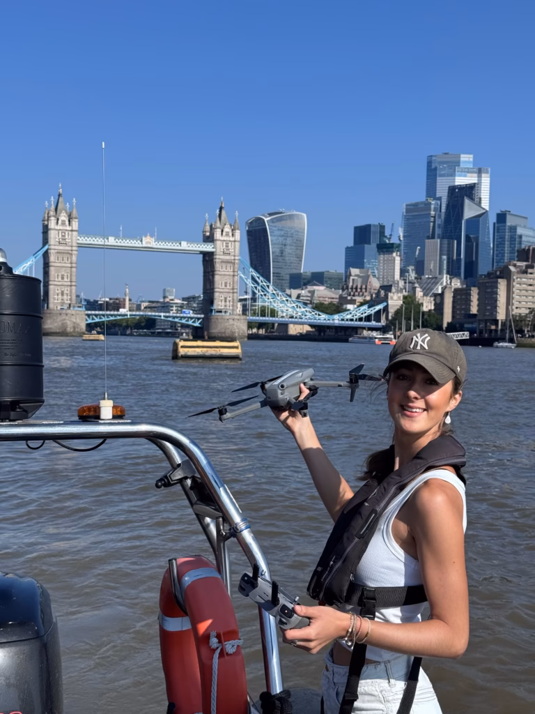 Drone operator Ella Goldsmith holding up her drone on our RIB, with Tower Bridge and the City behind