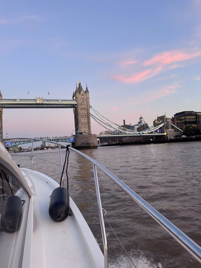 The foredeck of a boat approaching Tower Bridge from the Upper Pool at dusk